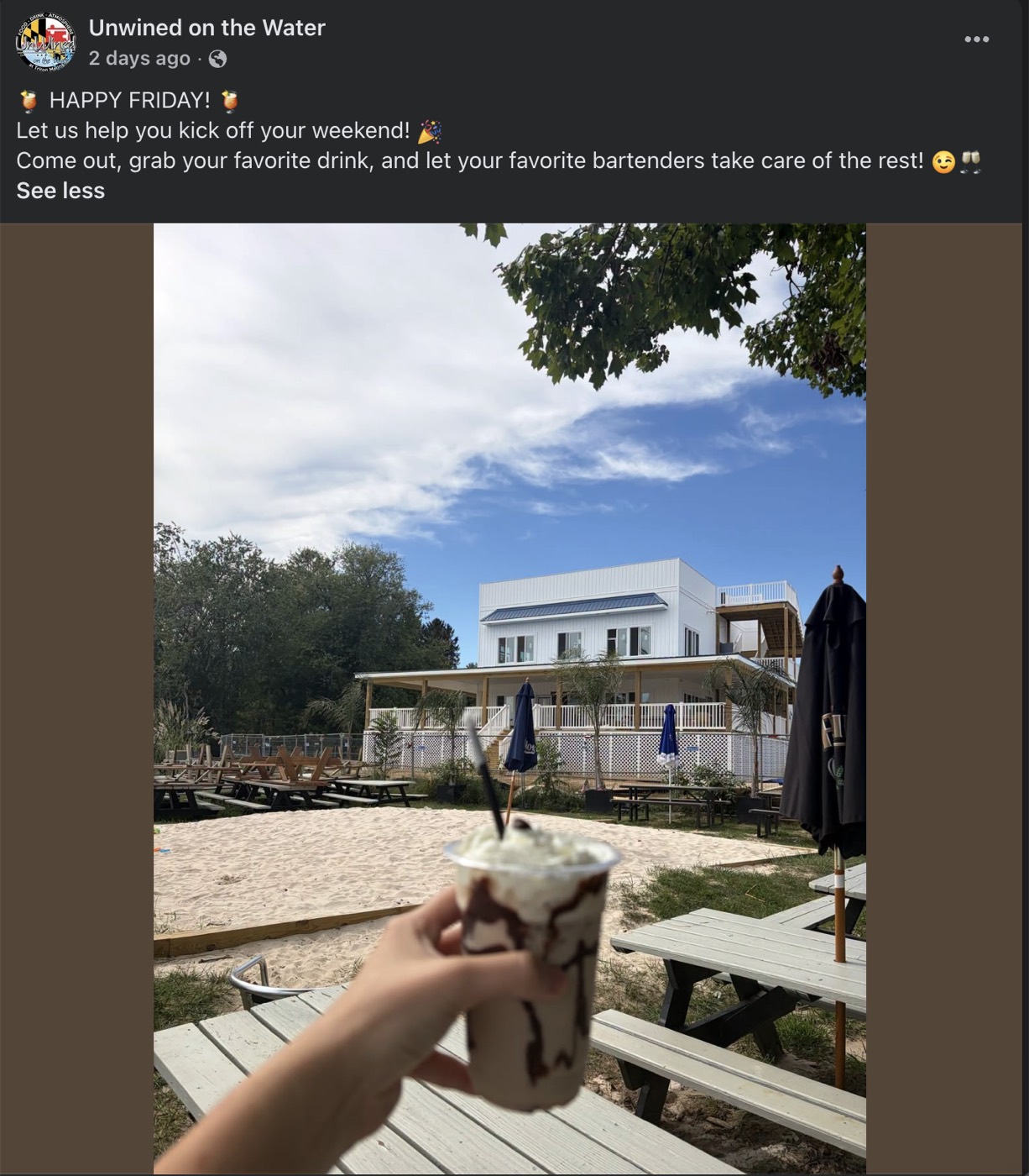 A frozen drink held up beside the sandy Tiki Bar area and rebuilt restaurant